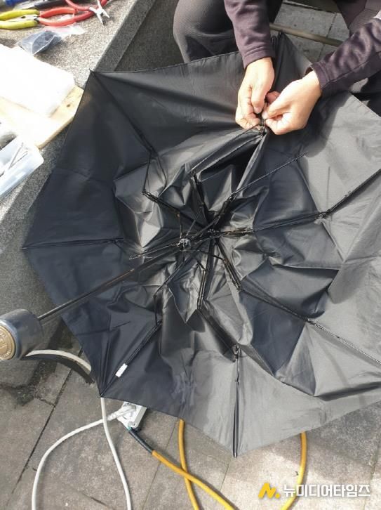 고장 난 우산을 수리하는 모습