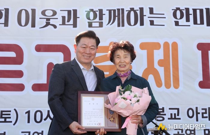 박승원 광명시장이 지난 1일 개봉교 아래 목감천 일대에서 열린 ‘제8회 광명2동 한마당 축제’에 참석해 어르신 환경봉사대 참여 어르신에게 시창 표창을 수여하고 기념사진을 촬영하고 있다.