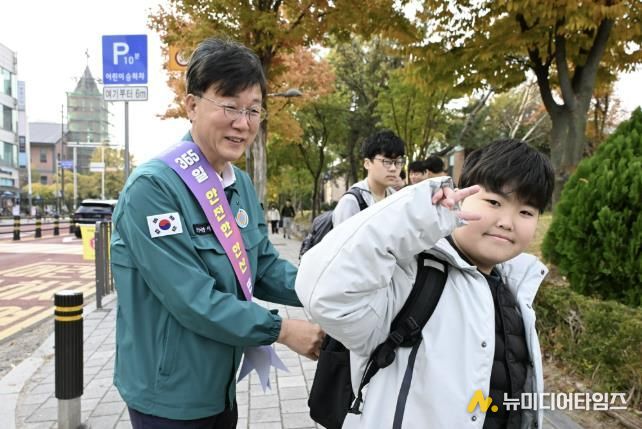 이민근 안산시장(사진 왼쪽)이 학현초등학교 앞에서 ‘스쿨존 어린이 교통안전 캠페인’을 진행하며 등교하는 어린이의 가방에 '홍이 키링'을 달아주고 있다.