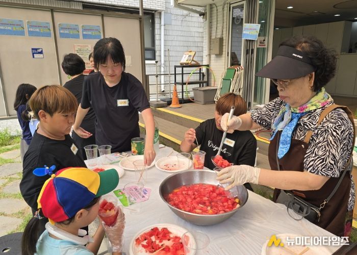 '우리마을 은빛 놀이터’프로그램에 참여한 어르신이 아이들에게 수박화채를 나눠주고 있다.